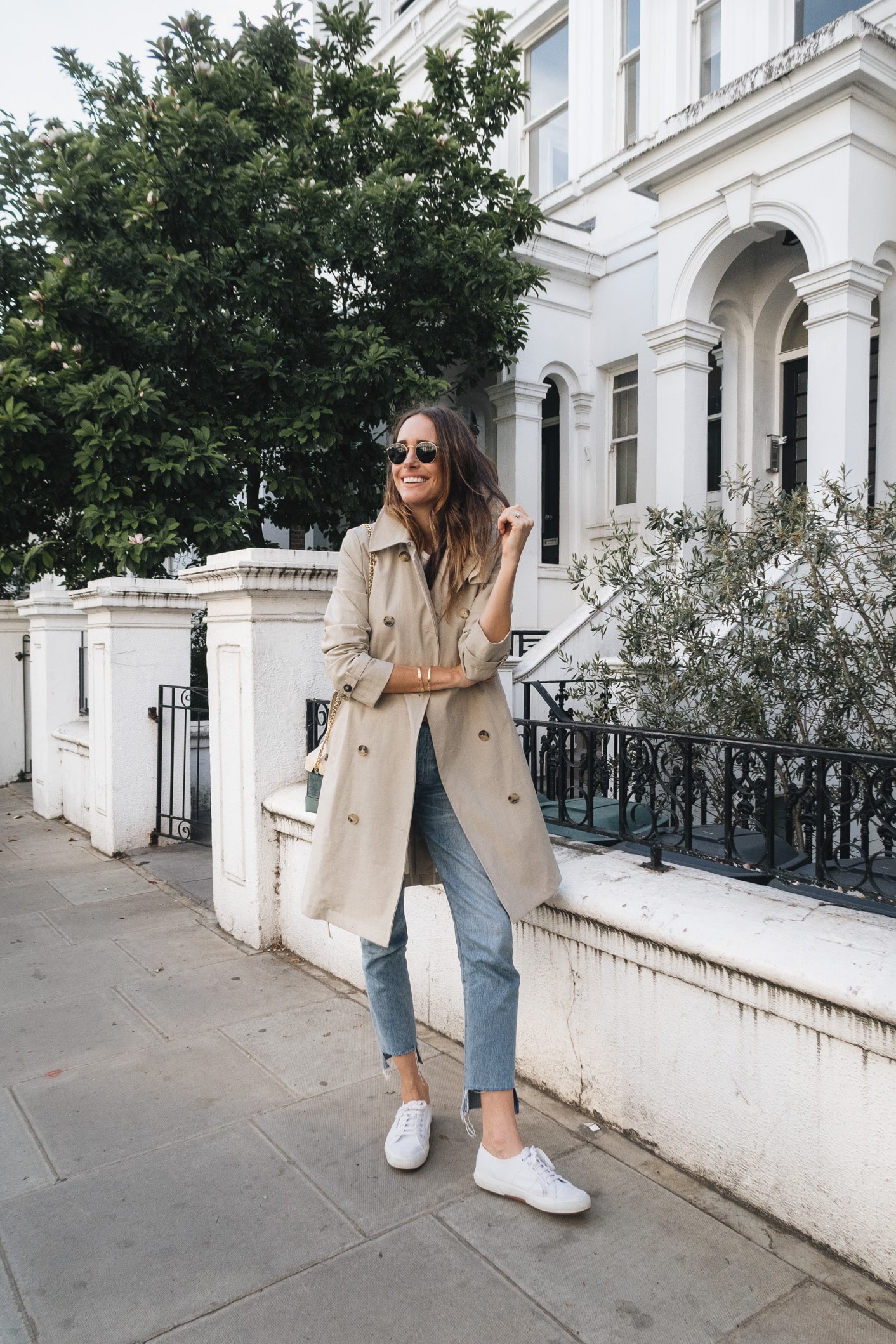 Louise Roe wearing a classic trench coat jeans and white sneakers in London