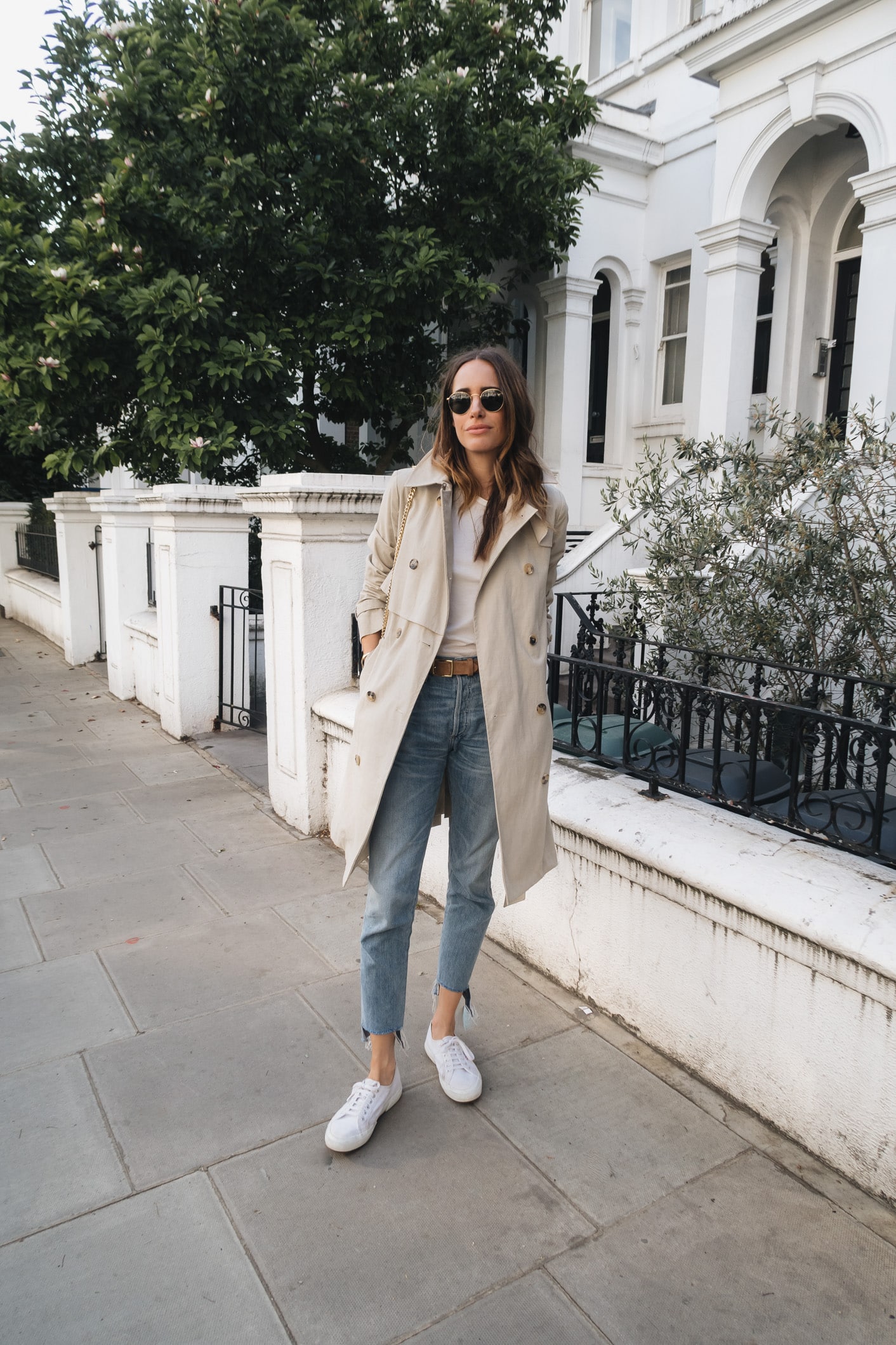Louise Roe wearing a classic trench coat jeans and white sneakers in London