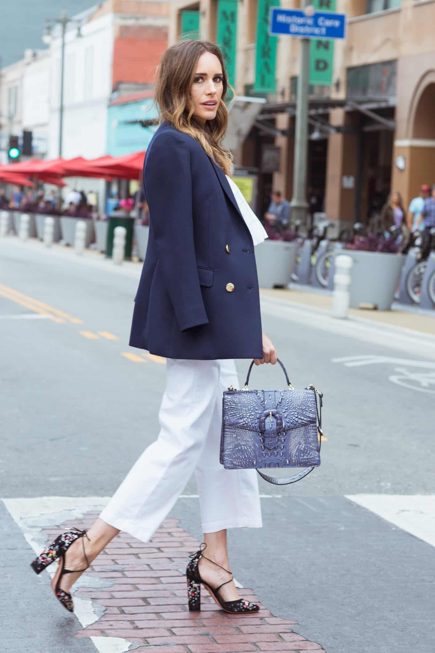 Louise Roe wearing white outfit with blue blazer and Brahmin bag