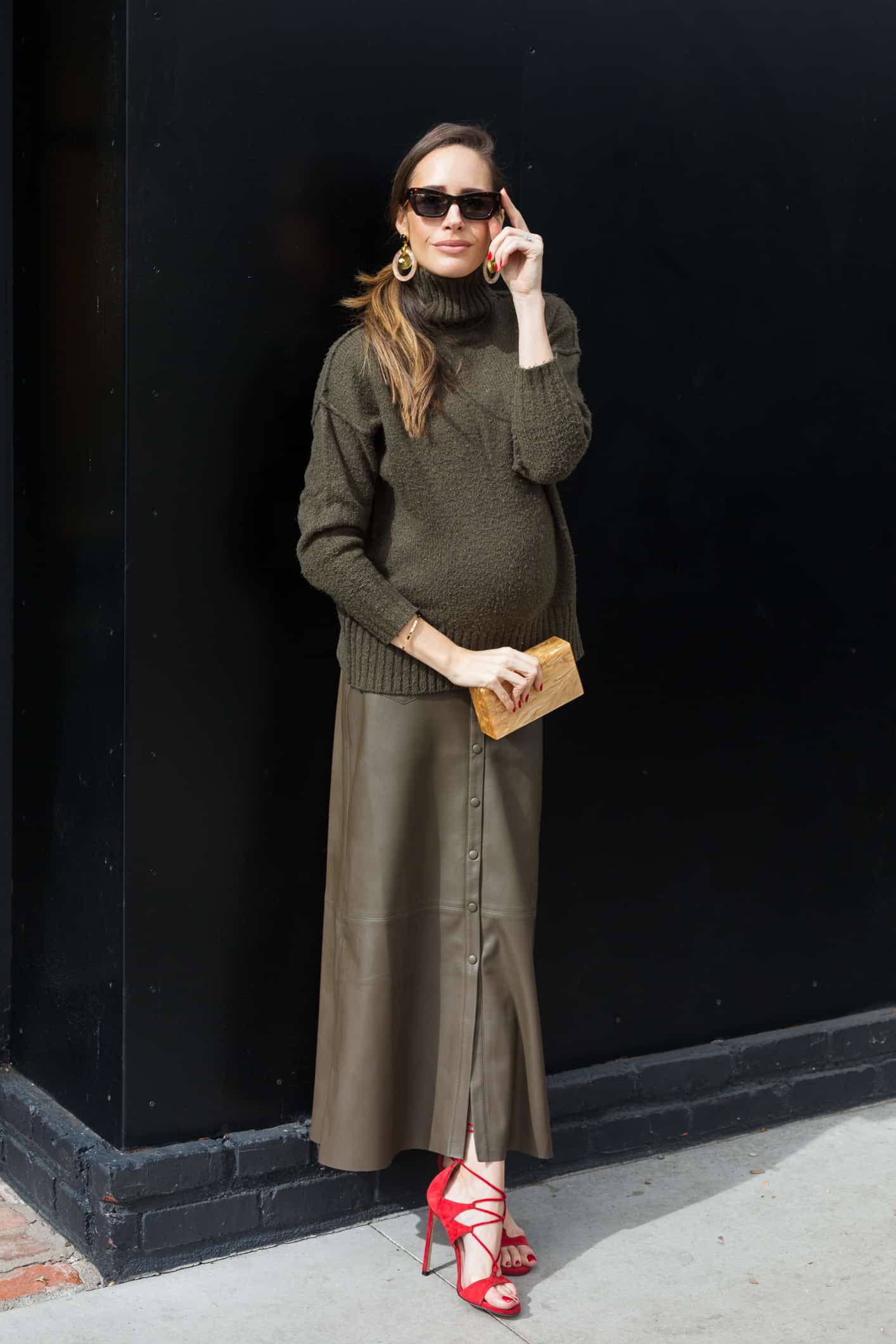 Louise Roe wearing a monochrome olive outfit with turtleneck leather skirt and red heels