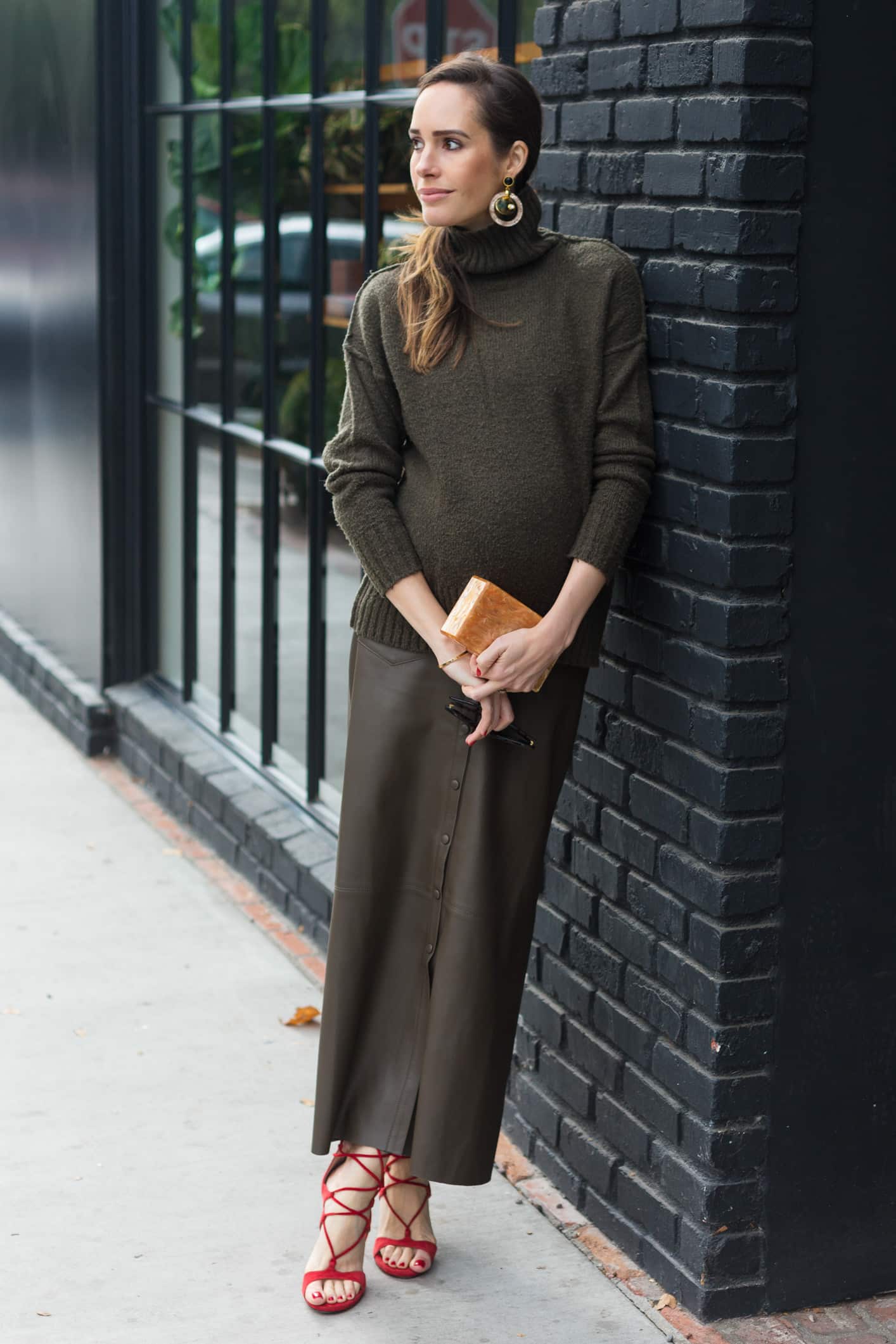 Louise Roe wearing a monochrome olive outfit with turtleneck leather skirt and red heels